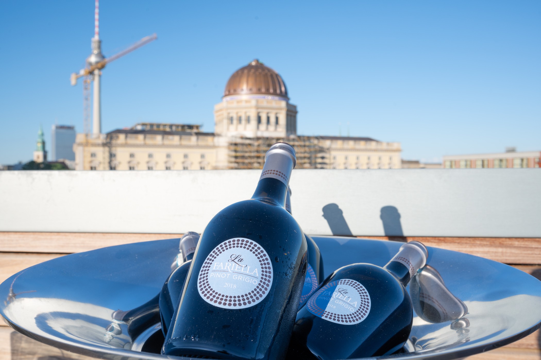 Weinflaschen in einer Kühlschale auf einer Dachterrasse am Schinkelplatz in Berlin-Mitte mit Blick auf das Humboldt Forum und den Fernsehturm.