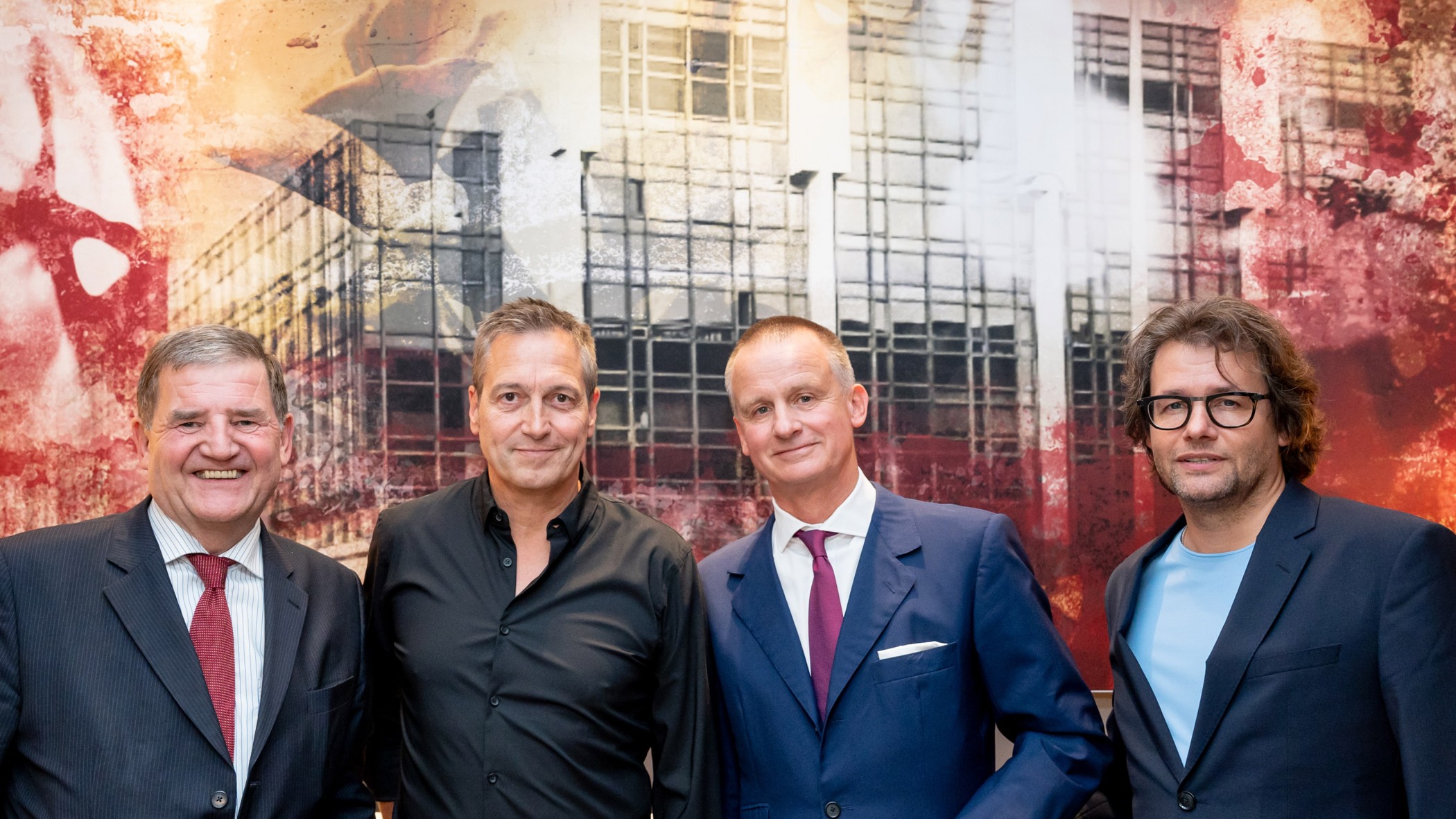 Vier Männer vor einem großformatigen rot-grauen Kunstwerk, darunter Dieter Nuhr, Uwe Schmitz und Dirk Geuer
