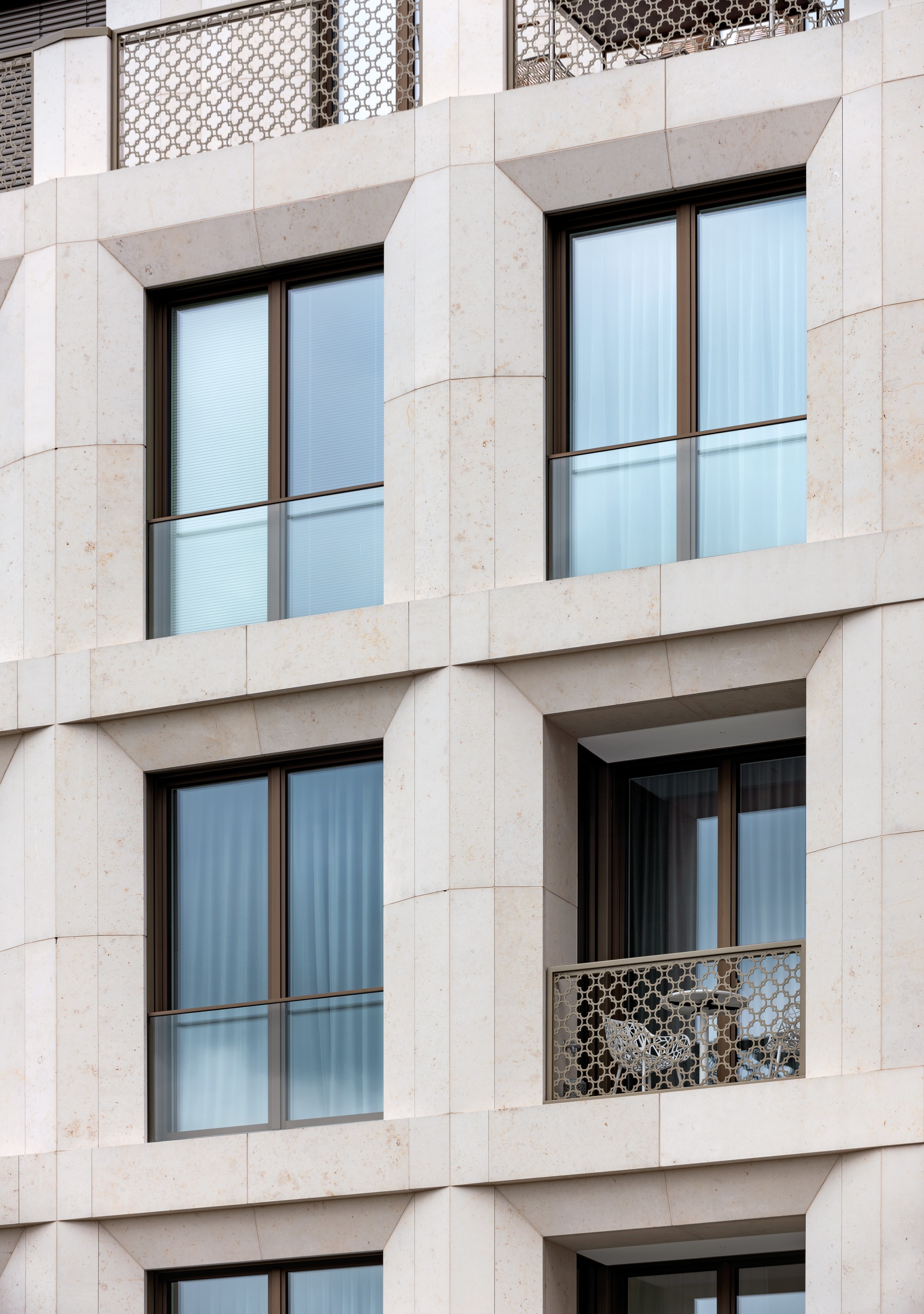 Detailansicht der Natursteinfassade mit modernen Fenstern und filigranen Balkongeländern am Schinkelplatz in Berlin-Mitte.