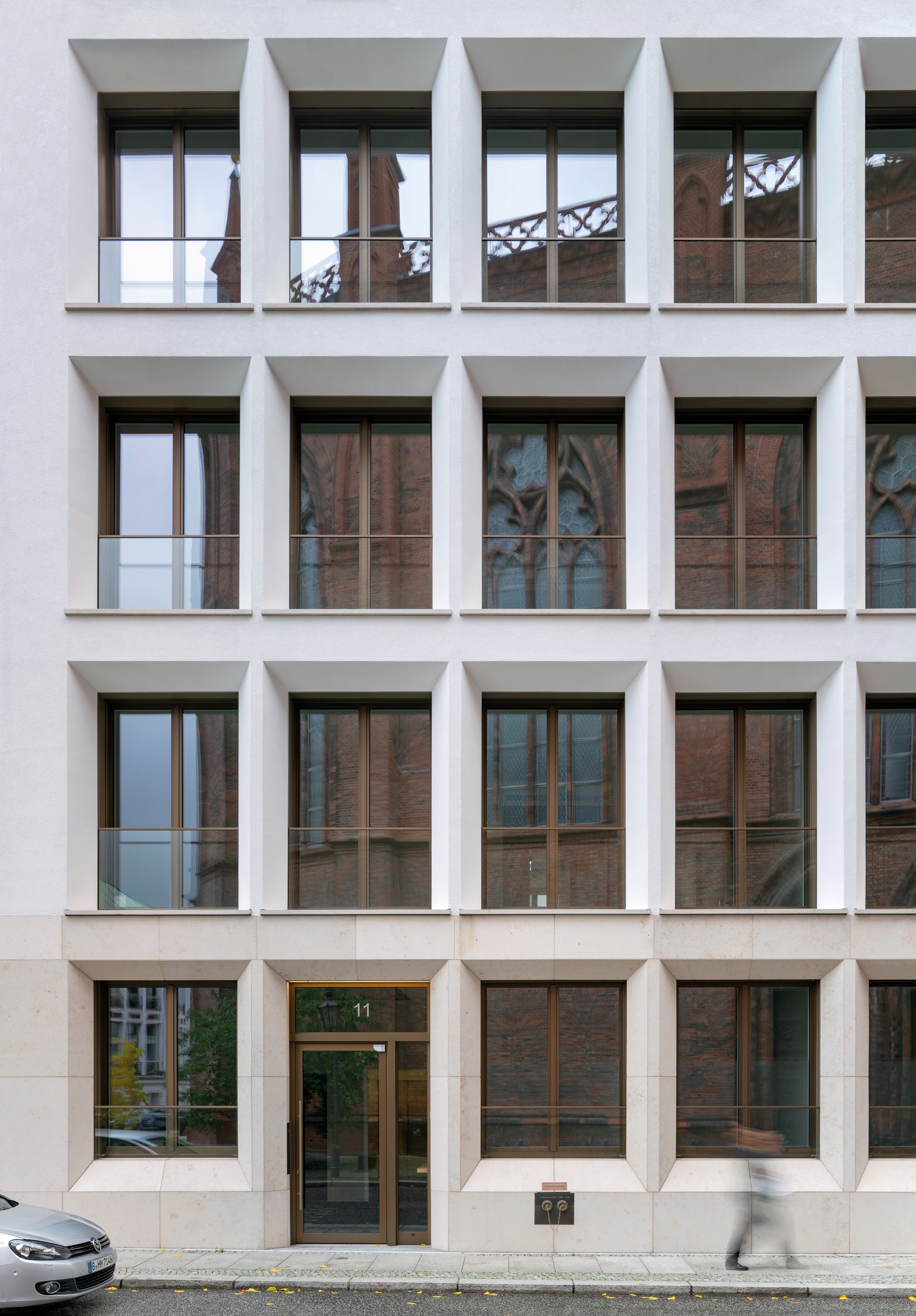 Moderne Wohnarchitektur am Schinkelplatz in Berlin-Mitte mit heller Natursteinfassade und geometrischen Balkonen.