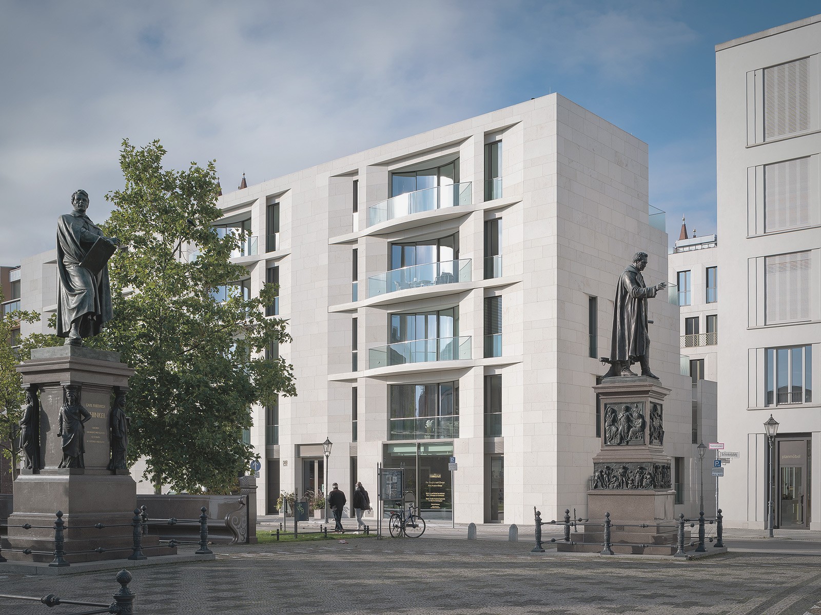 Moderne Wohnresidenzen am Schinkelplatz in Berlin-Mitte mit den Statuen Karl Friedrich Schinkels und Christian Peter Beuths im Vordergrund.
