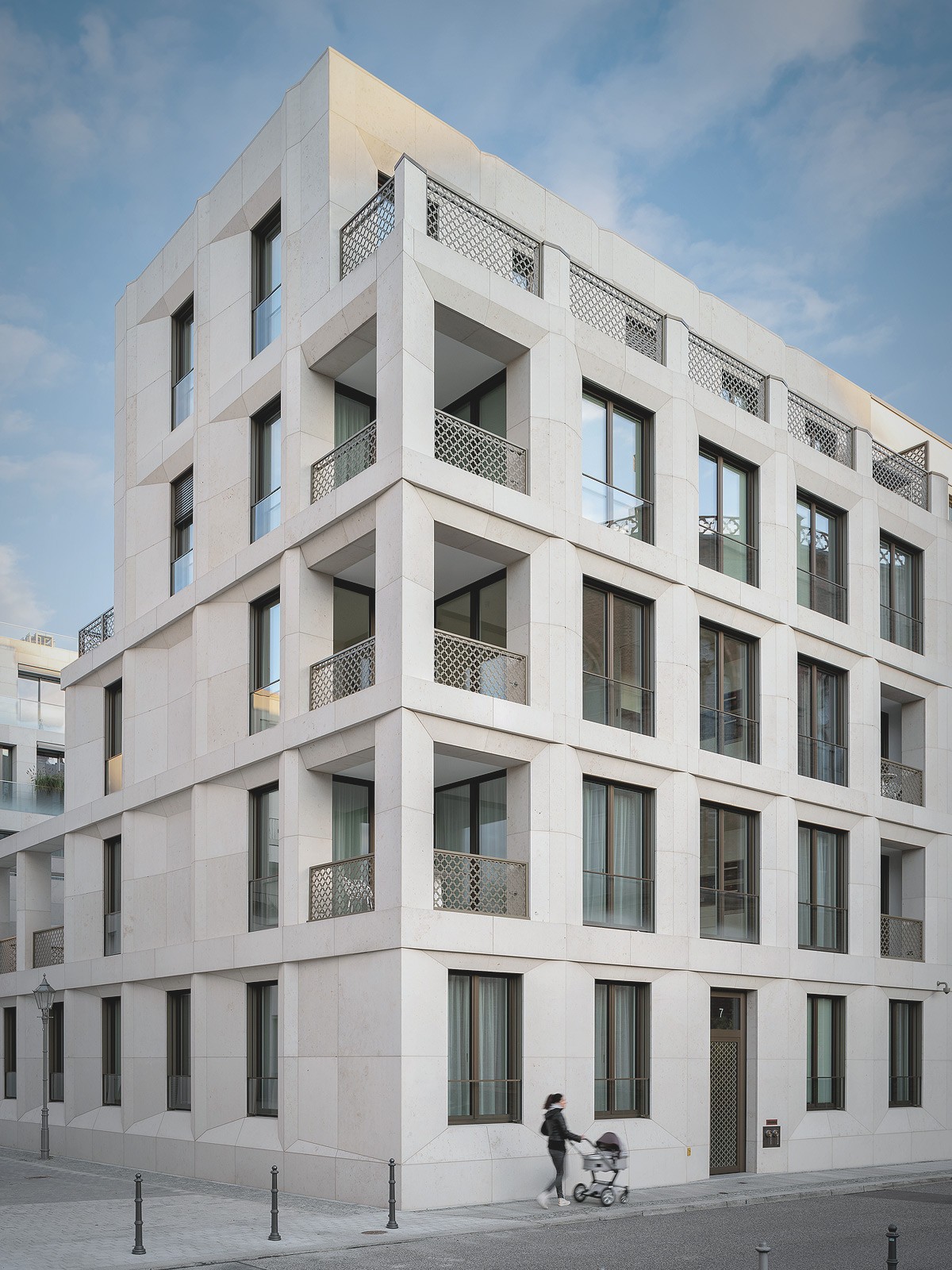 Moderne Wohnarchitektur am Schinkelplatz in Berlin-Mitte mit heller Natursteinfassade und geometrischen Balkonen.