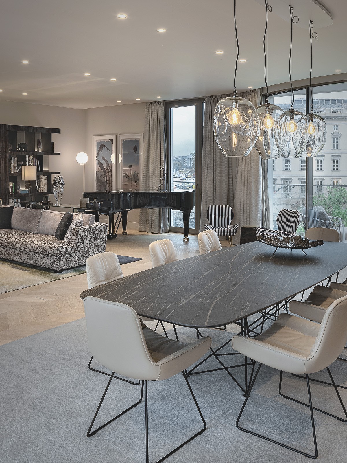 Elegantes Wohnzimmer mit großem Esstisch, Designbeleuchtung und Flügel in einer luxuriösen Wohnung am Schinkelplatz in Berlin.