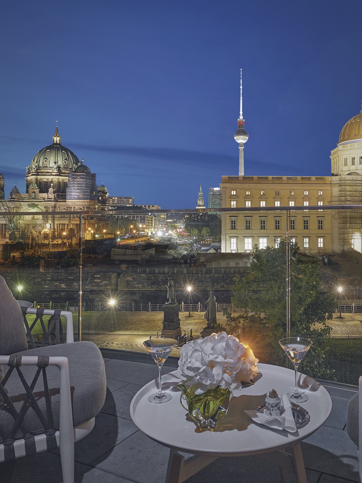 Abendlicher Terrassenblick am Schinkelplatz in Berlin-Mitte mit Berliner Dom, Fernsehturm und beleuchtetem Humboldt Forum.