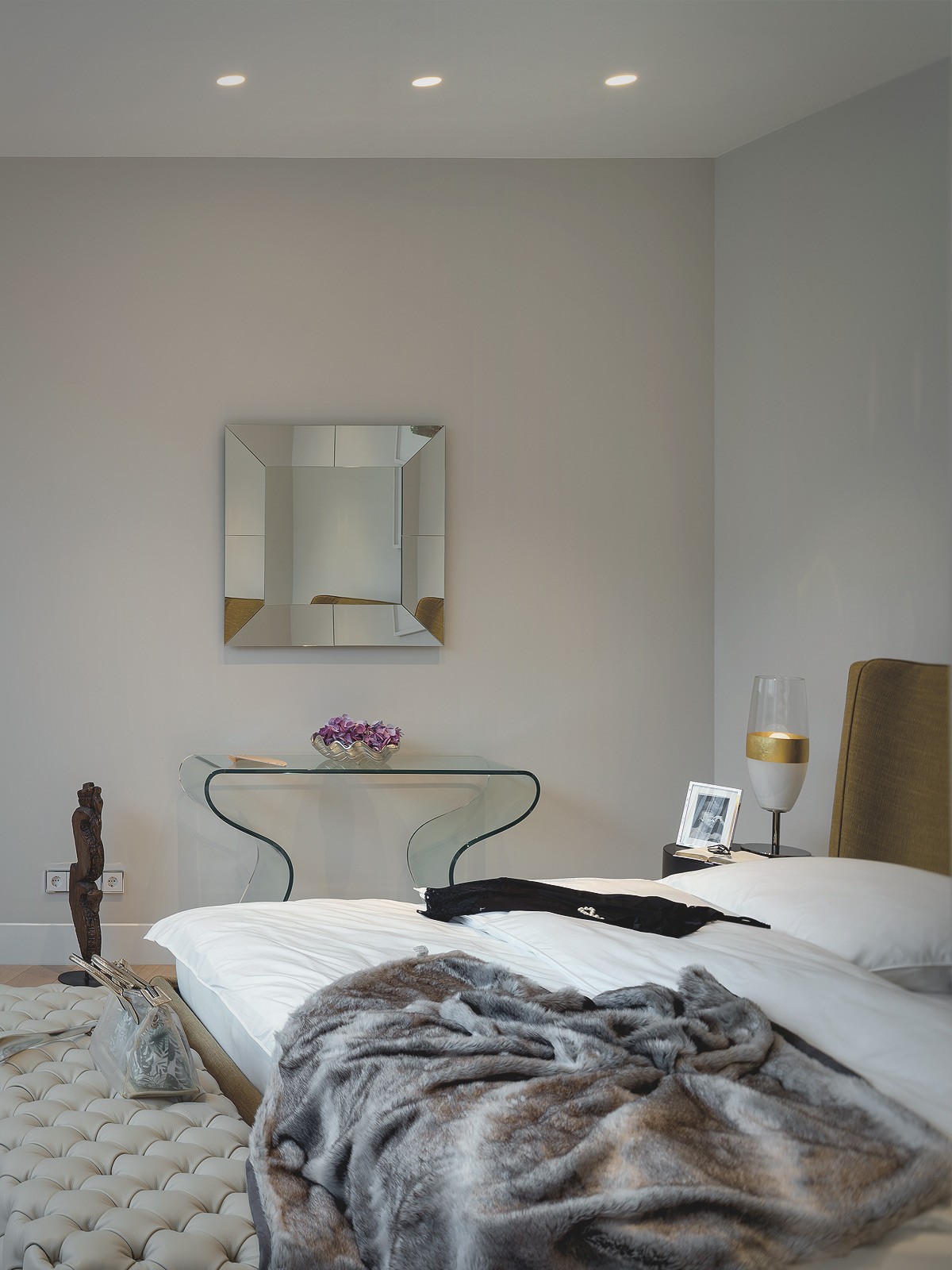 Elegantes Schlafzimmer einer Luxuswohnung am Schinkelplatz in Berlin mit Designerbett, Glas-Konsole und moderner Wanddekoration