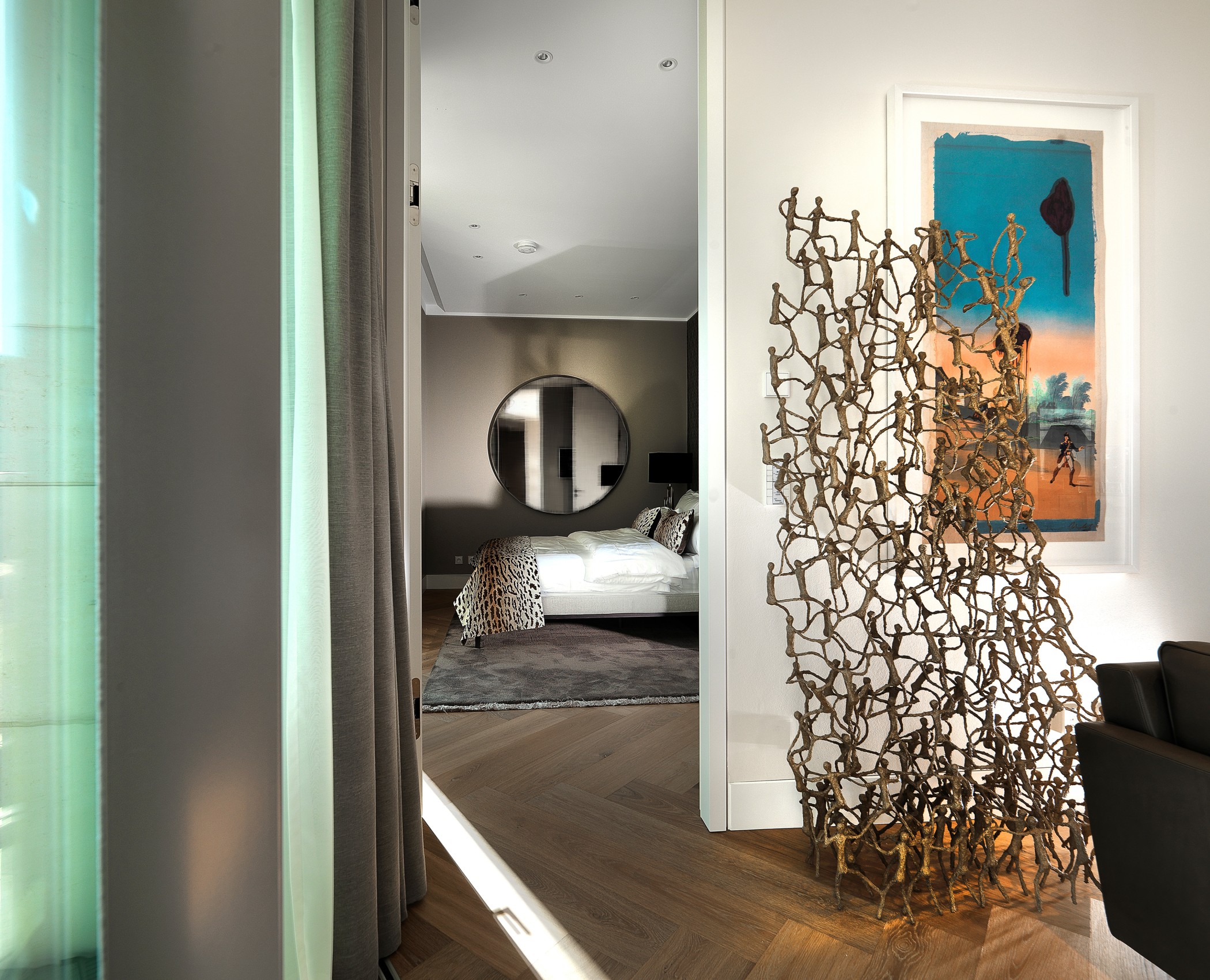 Innenansicht einer Designwohnung am Schinkelplatz in Berlin-Mitte mit Blick ins Schlafzimmer, moderner Kunst und Skulptur.