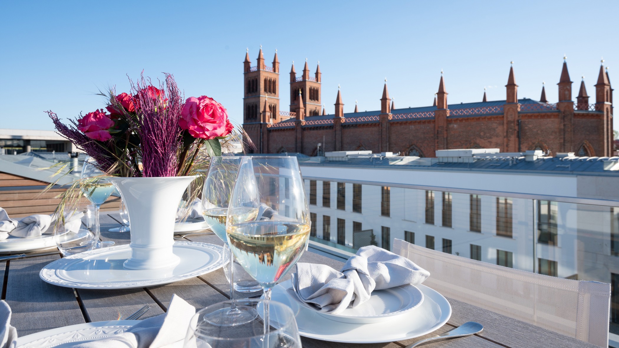 Gedeckter Tisch mit Rosen und Weingläsern auf einer Dachterrasse mit Blick auf die Friedrichswerdersche Kirche