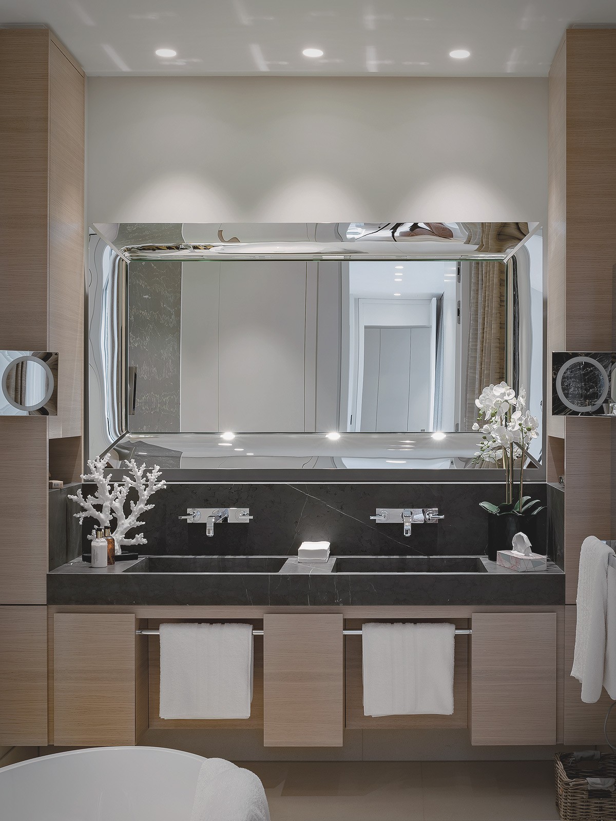 Luxuriöses Badezimmer am Schinkelplatz in Berlin mit großem Wandspiegel, dunkler Naturstein-Waschtischanlage, modernen Armaturen und eleganten Holzfronten.